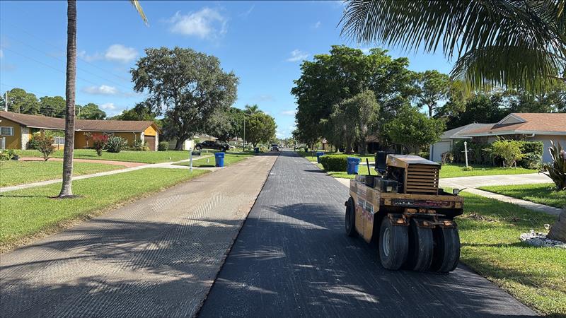 Paving equipment applying asphalt to a neighborhood roadway